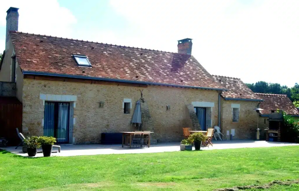 Gîte en pierre avec un toit rouge, offrant un cadre charmant et accueillant pour les visiteurs.