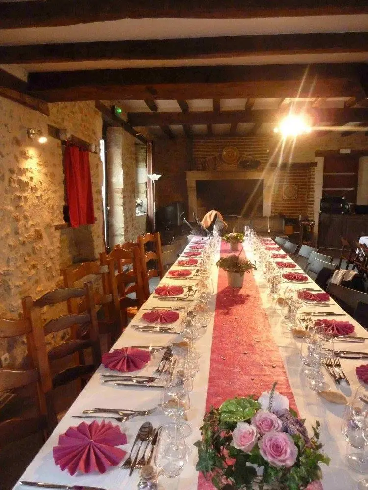 Une longue table élégamment dressée avec des serviettes roses, prête pour un événement privé dans un gîte de charme.